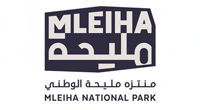 الصورة عبارة عن شعار"Mleiha National Park " مكتوبة باللون برتقالي مع خلفيه بيضاء